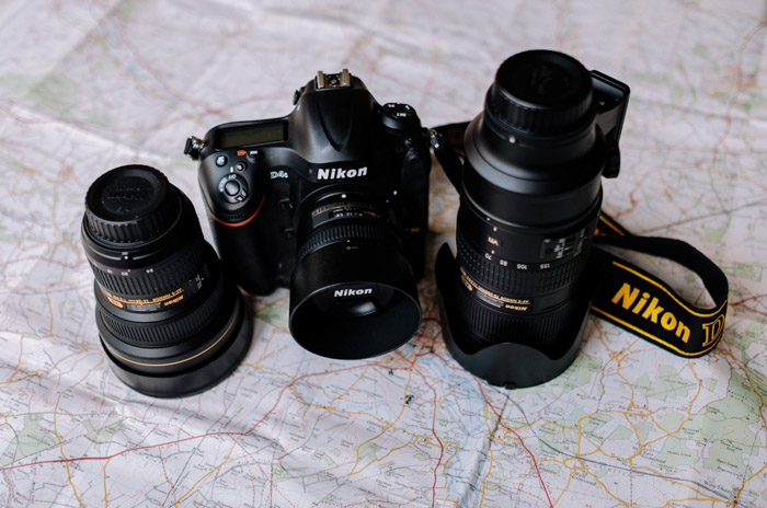 A Nikon dslr camera and two different wide angle lenses resting on a map