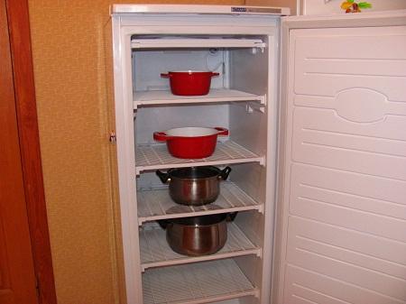 Быстро разморозить холодильник можно с помощью кастрюль, наполненных теплой водой 